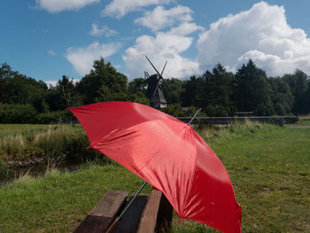 Red umbrella on field against sky