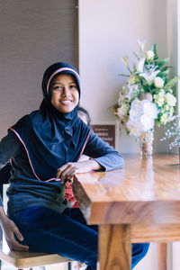 Portrait of girl wearing hijab sitting at table in cafe