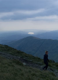 Rear view of man standing on mountain against sky