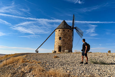 Rear view of man standing on mountain against sky