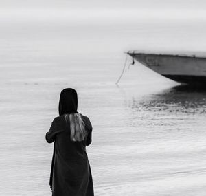 Rear view of woman standing at sea shore against sky