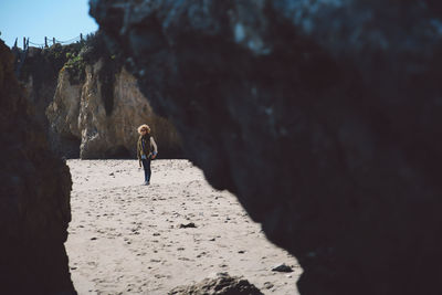 Mid distance view of mid adult woman at beach seen through rocks