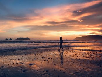 Silhouette man standing on beach against sky during sunset