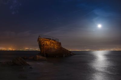 Abandoned ship in sea against sky at night 