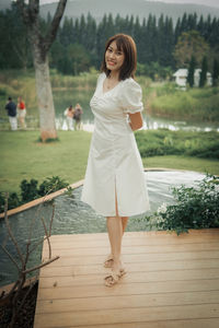 Portrait of young woman standing against trees