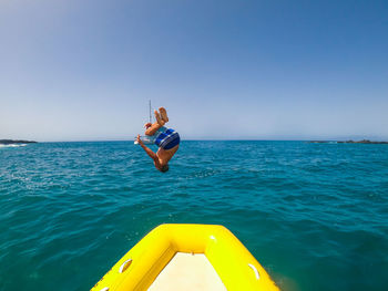 Full length of boy jumping in sea against sky