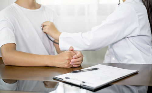 Midsection of doctor examining patient in hospital