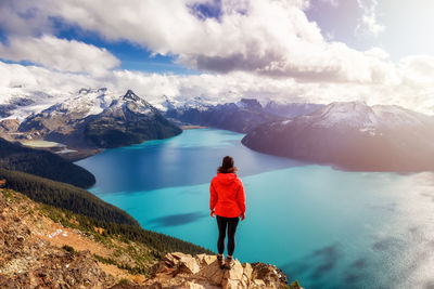 Rear view of woman standing on rock against sky