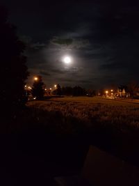 Illuminated street against sky at night