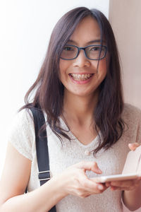 Portrait of smiling young woman holding mobile phone