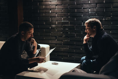 Young man sitting on table against wall