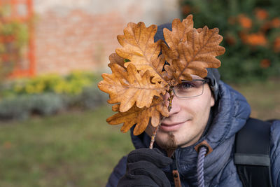 Portrait of young man holding autumn leaf