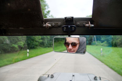 Young woman riding vehicle reflecting on mirror