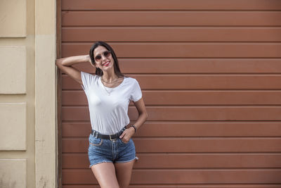 Portrait of young woman standing against wall