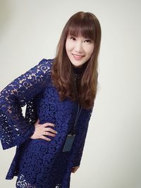 Portrait of smiling young woman standing against wall