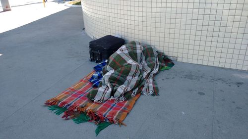 Person sleeping on street in blanket by luggage