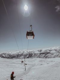 Overhead cable car on snowcapped mountains against sky