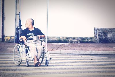 Man sitting on bicycle against wall