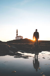 Rear view of man reflecting on puddle against sky