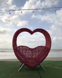 Close-up of heart shape on beach against sky