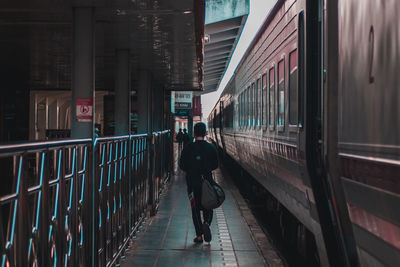 Rear view of man walking on railroad station platform