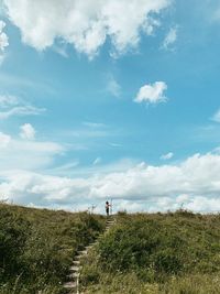 Low angle view of boy standing on hill against sky