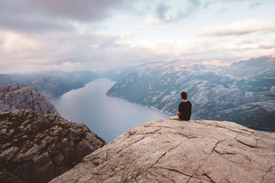 Man sitting in rock at edge of cliff at preikestolen, norway