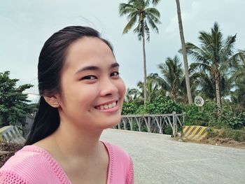 Portrait of young woman against palm trees