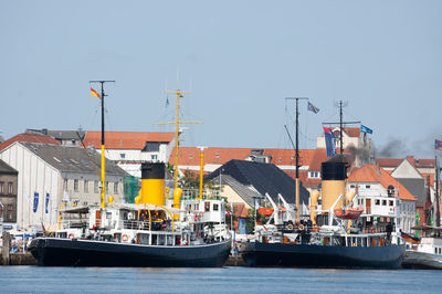 Boats moored at harbor against clear sky