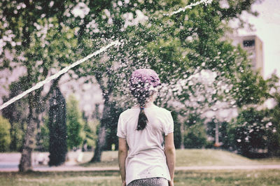 Rear view of woman standing against trees