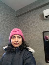 Portrait of woman wearing hat against wall