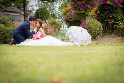 Newlywed couple romancing on grassy field at public park