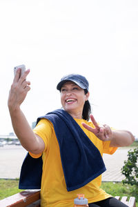 Young man using mobile phone against sky