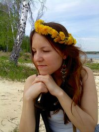 Young woman wearing flower wreath in her hair while sitting at beach