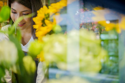Smiling florist working in store seen through glass window