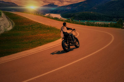 Man riding motorcycle on road against mountain