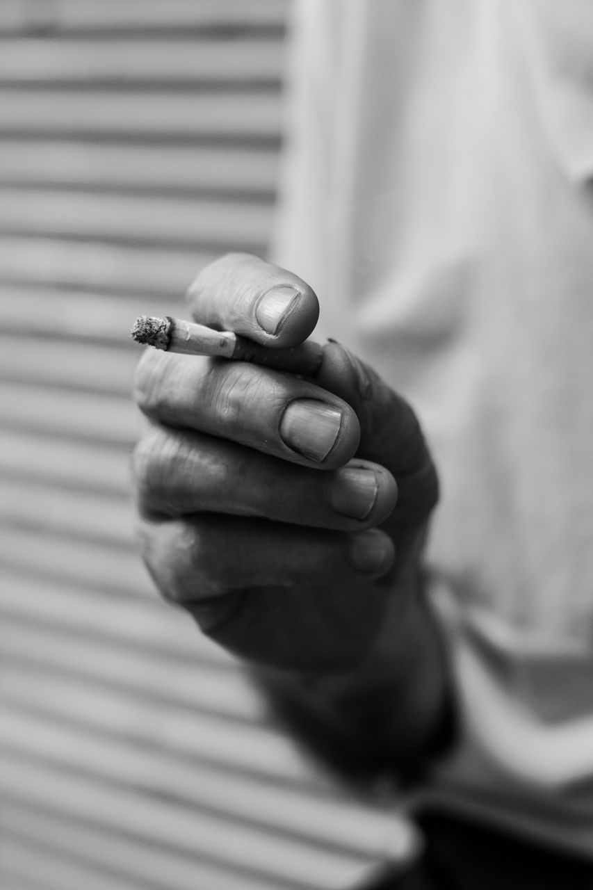 CLOSE-UP OF HANDS HOLDING CIGARETTE