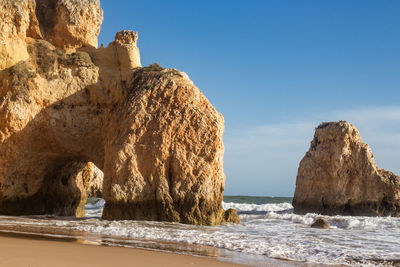 Rock formation on beach against sky