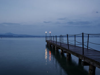 Pier over sea against sky at dusk