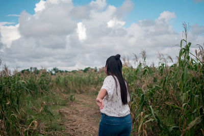 Rear view of woman standing on field against sky