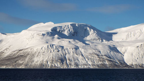 Scenic view of snowcapped mountains by sea against sky