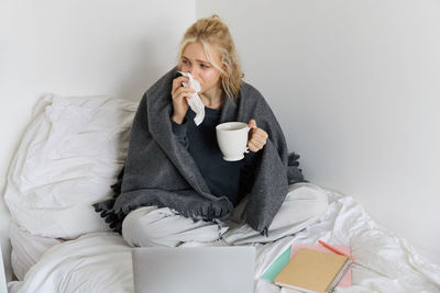 Portrait of young woman sitting on bed at home