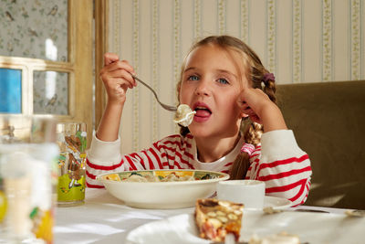 Child eats dumplings sitting at the table at home