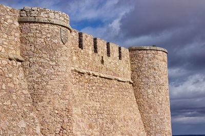 Low angle view of fort against cloudy sky