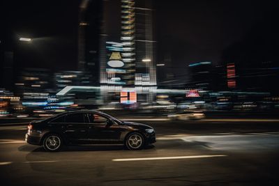 Cars on illuminated city street at night