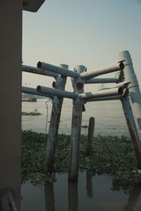 Close-up of railing by river against clear sky