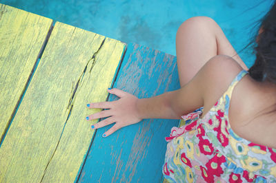 High angle view of girl sitting on wood on swimming pool
