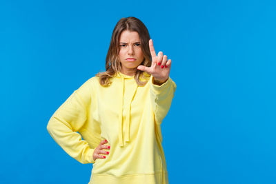 Portrait of young woman against blue background