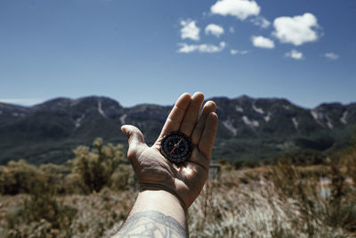 Man's hand holding a compass to orient himself on the mountain person