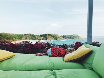 Girl lying on bed against sea